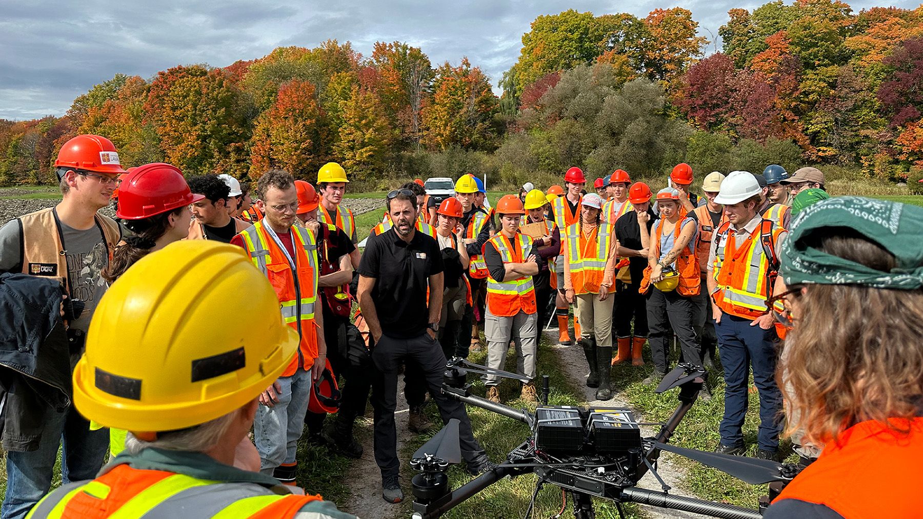 Groupe d'étudiants avec un enseignant rassemblés autour d'un drone dehors en été