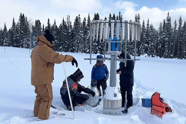 Quatre personnes dans la neige autour d'un instrument de recherche