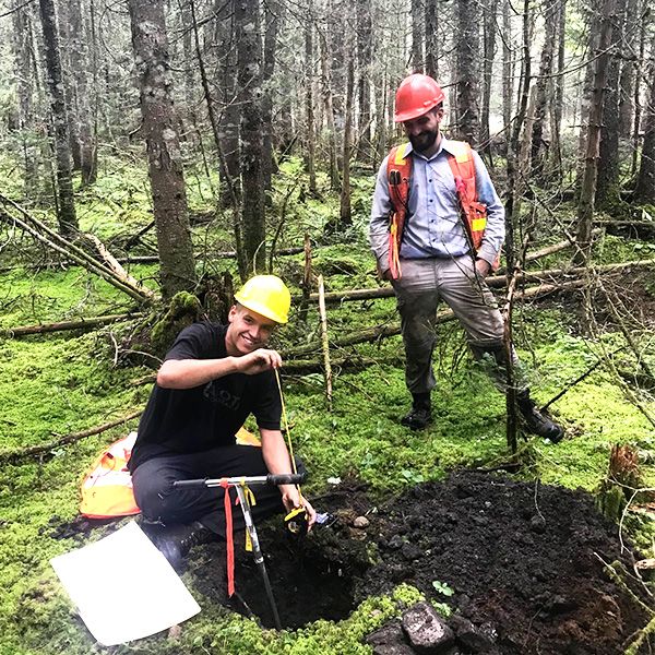 Deux étudiants en forêt creusant un trou.