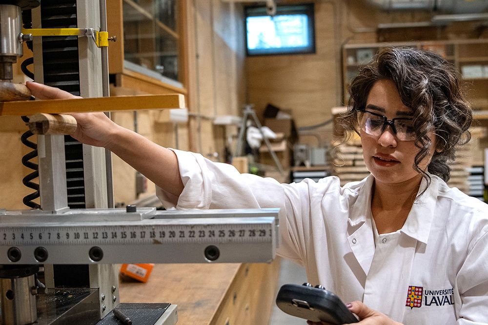 Femme avec lunettes et sarrau faisant des expériences sur du bois