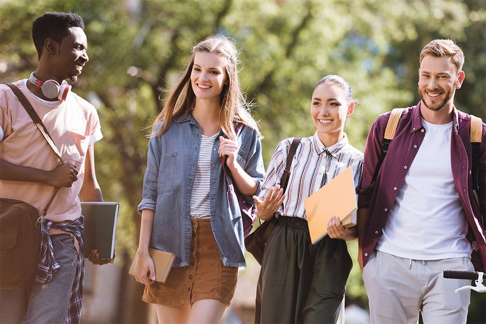 Groupe de 4 étudiants qui marchent dehors l'été